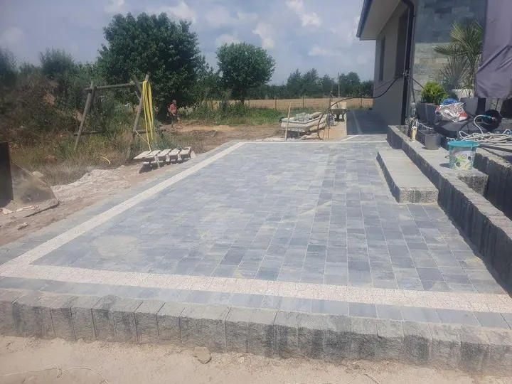 Podwyższony taras z kostki brukowej obłożony palisadą granitową